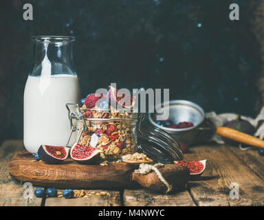 Healthy vegan breakfast. Oatmeal granola with bottled almond milk, honey, fresh fruit and berries over wooden table background, copy space. Clean eati Stock Photo