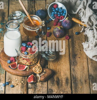 Healthy vegan breakfast. Oatmeal granola with bottled almond milk, honey, fresh fruit and berries on hoard over rustic wooden table background, copy s Stock Photo