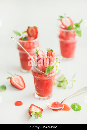Healthy low calorie summer treat. Strawberry and champaigne granita, slushie or shaved ice dessert in glasses with mint, white background. Clean eatin Stock Photo