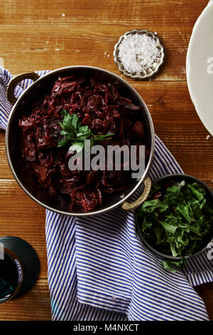 Vertical image of red cabbage with beetroot braised in red wine sauce served with sea salt and parsley. Vegetarian main dish concept. Flatlay composit Stock Photo
