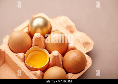 Half Dozen of chicken eggs in colorful cardboard container with one golden egg Stock Photo