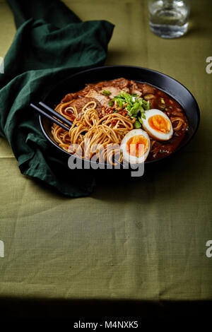 Japanese ramen with pork belly, mushrooms and marinated eggs on green linen tablecloth Stock Photo