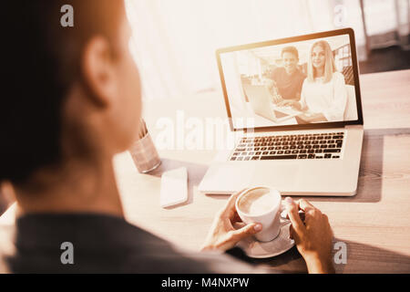 Composite image of businesspeople working over laptop at desk in creative office Stock Photo