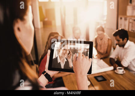 Composite image of businesswoman using digital tablet while discussing with colleagues Stock Photo
