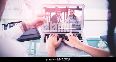 Composite image of business colleagues discussing over laptop Stock Photo
