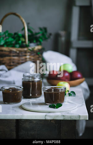 Apple jam and fresh apples on a rustic kitchen table Stock Photo