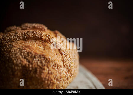 A close, detail shot of a loaf of sesame bread on a rich wood surface. Stock Photo