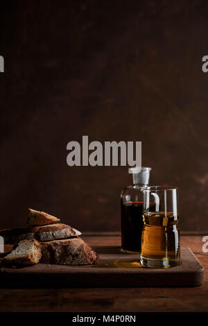 Chunks of rustic, rye bread on a rich wood surface with antique bottles of oil and vinegar. Stock Photo