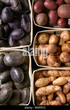 Variety of raw uncooked organic potatoes different kind and colors red, yellow, purple in market baskets. Food background. Top view, close up Stock Photo