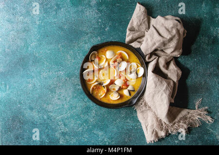 Vongole in tomato cream sauce for pasta in cast-iron pan with textile over turquoise texture background. Top view, copy space Stock Photo
