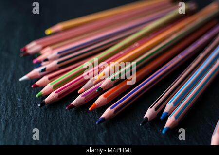 An array of coloring pencils spread out on a black slate Stock Photo