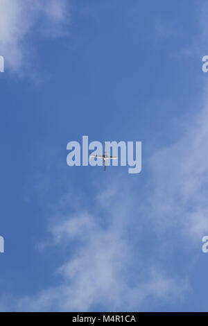 Airplane in distance, centered in a blue sky with light clouds. Room for writing. Stock Photo
