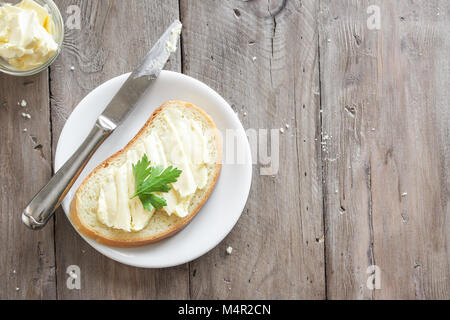 Butter and bread for breakfast, with parsley over rustic wooden background, copy space Stock Photo