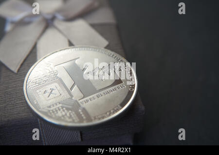 Silver litecoin  lying on the  grey gift box, grey stone background. Cryptocurrency gift concept, selective focus and place for text. Stock Photo