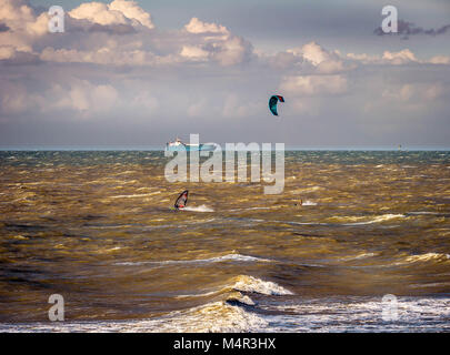 Kitesurfer, surfer and cargo-ship on stormy sea Stock Photo