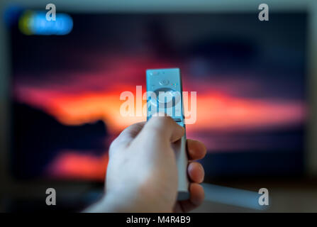 Male hand holding TV remote control. Stock Photo
