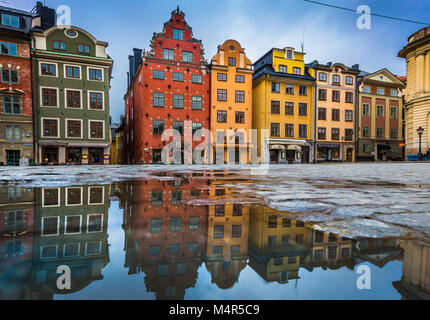 Classic view of colorful houses at famous Stortorget town square in Stockholm's historic Gamla Stan (Old Town) reflecting in a puddle with blue sky, c Stock Photo