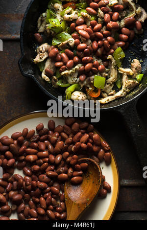 Beans are spread in a frying pan with pepper and chicken top view vertical Stock Photo