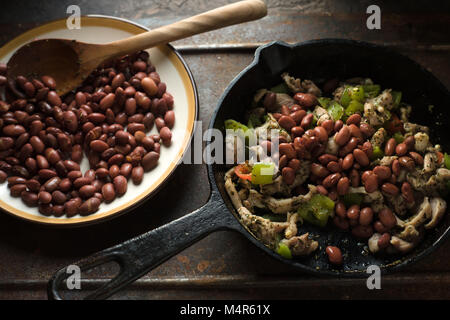 Beans are spread in a frying pan with pepper and chicken side view horizontal Stock Photo