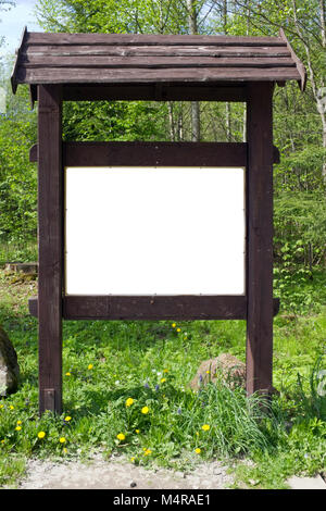 On the spring forest  glade there is a aged brown  wooden stand with information. Emty area isolated with patch Stock Photo