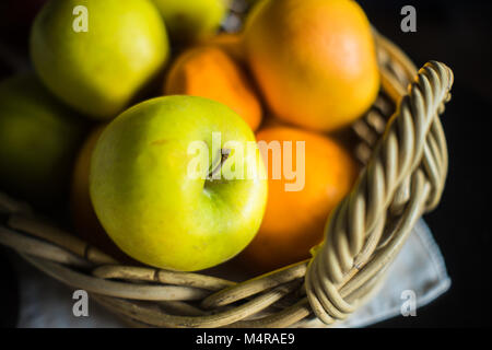 Rustic basket full of ripe fruits lika an oranges, tangerines and apples with copyspace Stock Photo