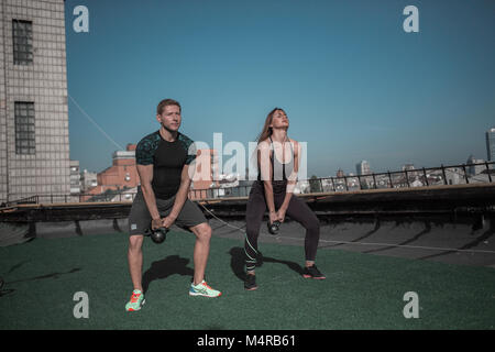 Sportive man and woman doing crossfit exrrcise on the roof. Stock Photo