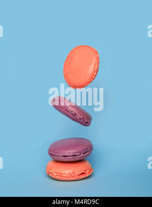French macarons in motion falling on the blue pastel colored background Stock Photo