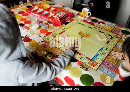 Monopoly board game being played by children friends inside a house on a table with colourful tablecloth at half-term in Carmarthenshire Wales UK Stock Photo