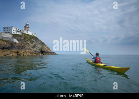 Sea kayaker beneath Baily Lighthouse, Howth Head, County Dublin, Ireland. Stock Photo
