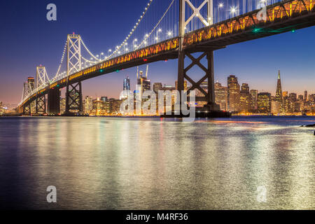 Classic panoramic view of famous Oakland Bay Bridge with the skyline of San Francisco illuminated in beautiful twilight after sunset in summer, Califo Stock Photo