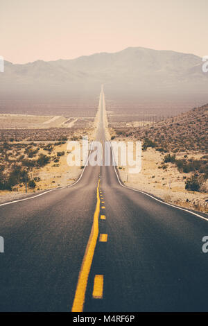 Classic panorama view of an endless straight road running through the barren scenery of the American Southwest Stock Photo