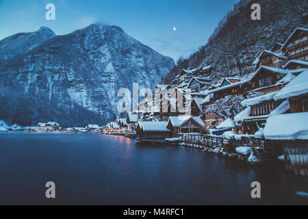 Classic postcard view of traditional wooden houses in famous Hallstatt lakeside town in the Alps in mystic twilight during blue hour at night, Austria Stock Photo