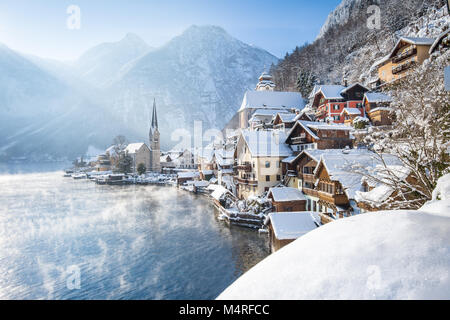 Classic postcard view of famous Hallstatt lakeside town in the Alps on a beautiful cold sunny day with blue sky and clouds at sunrise in winter, Salzk Stock Photo