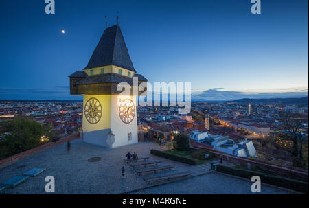 Panoramic aerial view of the old town of Graz with famous Grazer Uhrturm (clock tower) illuminated in beautiful evening twilight, Styria, Austria Stock Photo