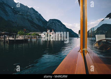 Classic view of traditional passenger boat gliding on Lake Konigssee with world famous Sankt Bartholomae pilgrimage church and Watzmann mountain on a  Stock Photo