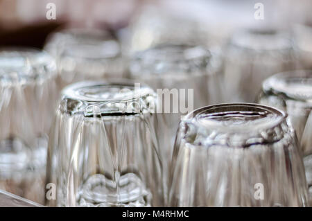 Selected focus close up on bottom of empty transparent drinking glasses placed upside down in group on a table. Stock Photo
