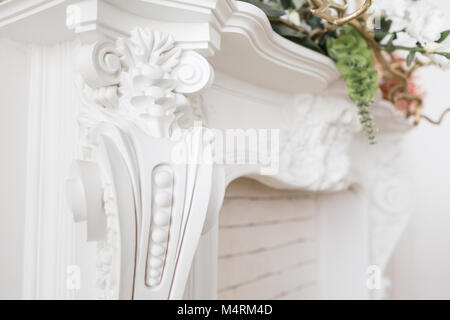 Expensive interior. Stucco elements on light luxury fireplace. White patterned. Mouldings element from gypsum. Roccoco style Stock Photo