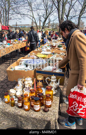 Customer with a red plastic bag and pharmacy bottles at the Mauerpark sunday flea market on an early spring day in Berlin, Germany - Europe. Stock Photo