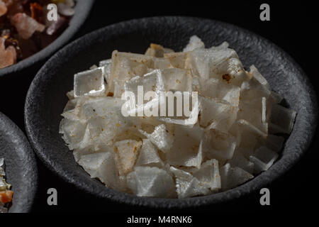 Macro collection, white sea salt pyramide flakes mixed with spices on black background Stock Photo