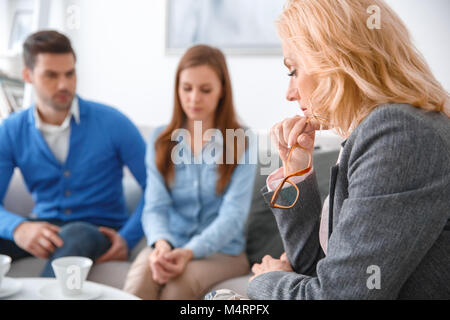 Young couple with psychologist family therapy therapist looking down thoughtful Stock Photo