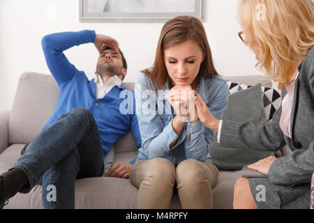 Young couple with psychologist family therapy man looking up irritated Stock Photo
