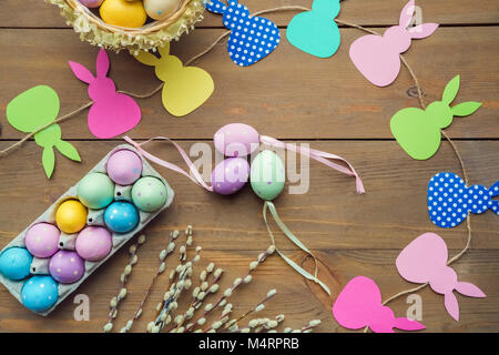 Colored eggs in a box and basket and decorations on the wooden background Stock Photo