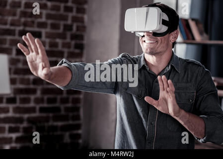 Radiant guy playing video games while wearing vr headset Stock Photo