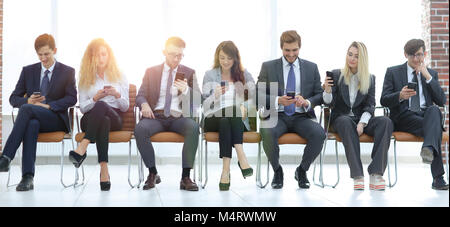 employees with smartphones sitting in the lobby Stock Photo