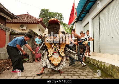 Local indonesian boys performing traditional lion dance with musical instruments on the street in Bali, Indonesia. Stock Photo