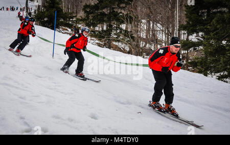 Ski Patrol Skiers carry fire hose on slope at Spring Ski Celebration at Jiminy Peak Mountain in Hancock, Massachusetts. Stock Photo