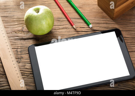 Green Apple And Blank Screen Digital Tablet On Wooden Table With Office Supplies Stock Photo