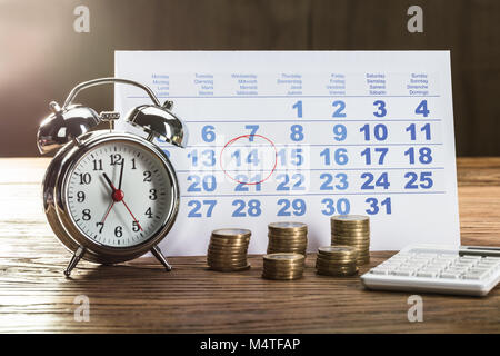 Tax Time On Alarm Clock With Coins, Calculator And Calendar Over The Wooden Table Stock Photo