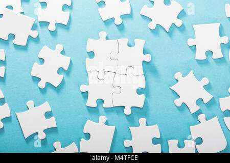 Elevated View Of White Jigsaw Puzzles On Blue Background Stock Photo