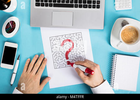 Elevated View Of A Businessman Drawing Labyrinth Maze On Paper With Office Supplies At Workplace Stock Photo